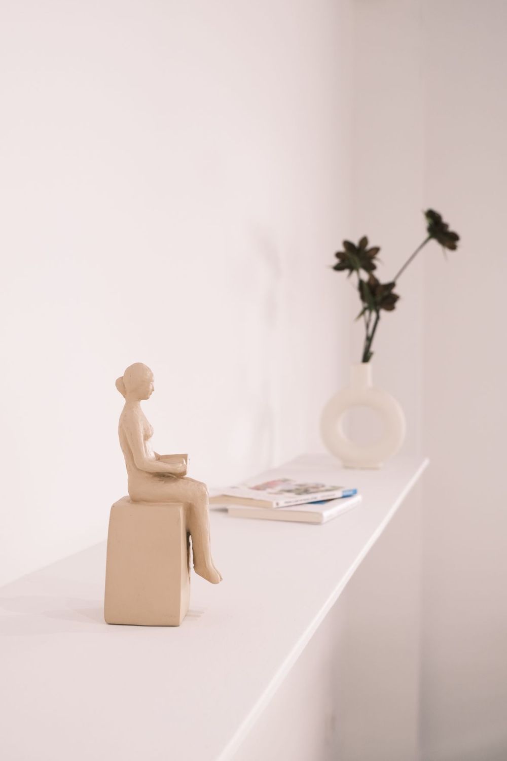 Étagère épurée avec une statuette, quelques livres et un vase
